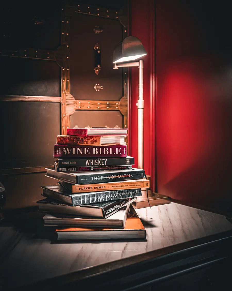 A stack of wine books under a desk lamp.