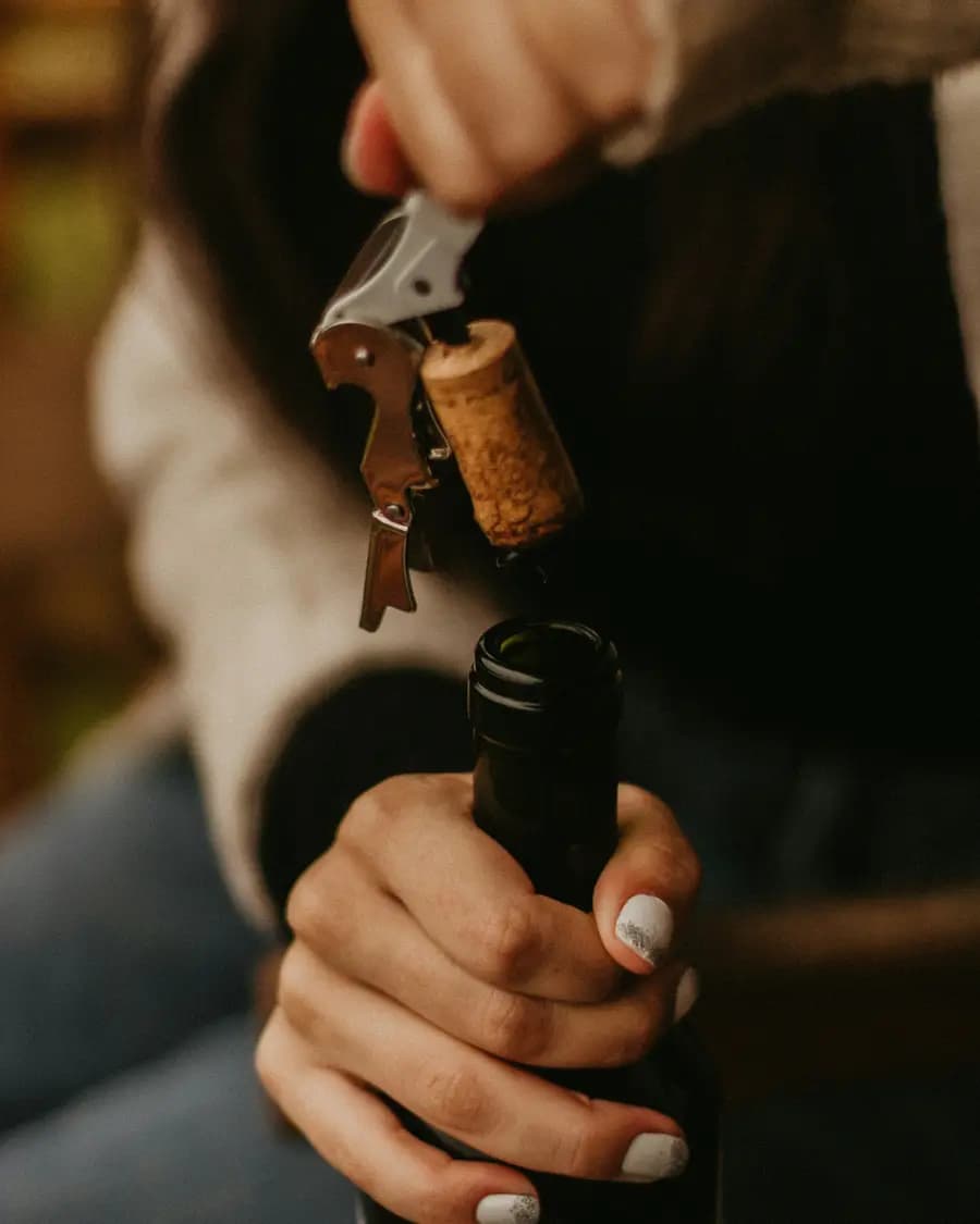 A cork being drawn from a bottle with a double-hinged waiter’s corkscrew.